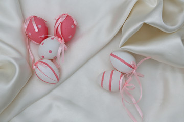 Small pink and white easter eggs on a white textile background