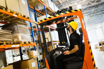 Warehouse worker doing logistics work with forklift loader © NDABCREATIVITY
