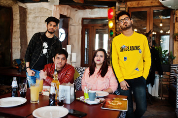 Group of asian friends sitting cafe. Happy indian people having fun together, sitting on couch.