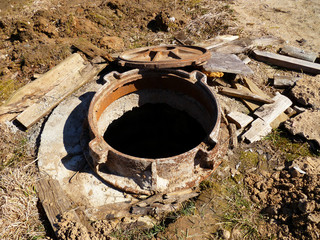 Sewerage hatchway, manhole. Rusty pit cover ring on construction site. Old cast rust iron sewerage...