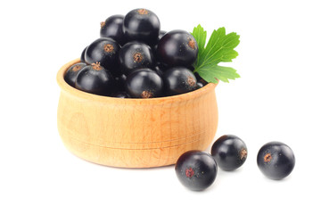 black currant in wooden bowl with green leaf isolated on white background.