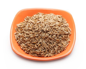Spelt grains, heap in bowl isolated on white background, macro