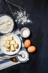 Ingredients for baking cupcakes on a black table close-up
