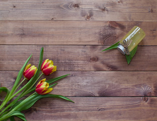 Spring Easter bouquet of tulip flowers with cosmetic product on wooden background.View with copy space
