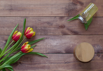 Flatlay Spring Easter bouquet of tulip flowers with cosmetic product and round box on wooden background.View with copy space.