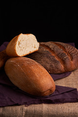 Bakery - gold rustic crusty loaves of bread and buns on black chalkboard background. Still life captured from above