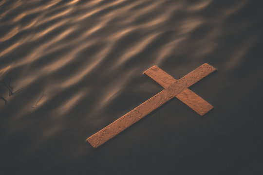 Wooden cross floating on water surface at dawn. Conceptual image baptism
