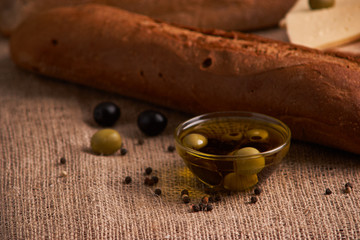 fresh bread baguette with olive oil, olives. cheese and rosemary on wooden background. Teasty breakfast