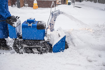 Man operating snow blower machine on the sidewalk in winter