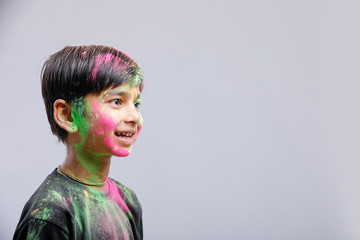 Indian little boy playing with the color and giving multiple expressions in holi festival 