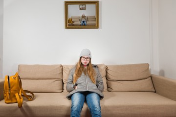 Teenaged girl sitting on sofa morning before going to school - Mornings are difficult.