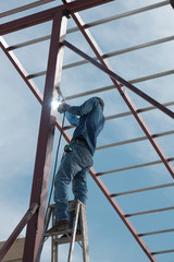 Amateur construction worker with no protection welding steel pole on ladder, working of the house roof