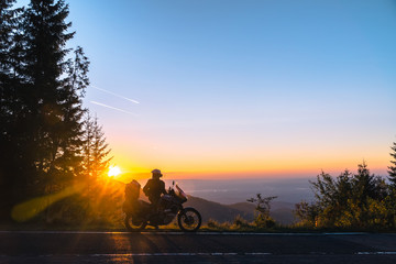 Silhouette of man biker and adventure motorcycle on the road with sunset light background. Top of mountains, tourism motorbike, vacation active lifestyle. Transfagarasan, Romania. © Sergey