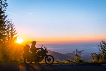 Foto op Plexiglas Silhouette of man biker and adventure motorcycle on the road with sunset light background. Top of mountains, tourism motorbike, vacation active lifestyle. Transfagarasan, Romania. © Sergey