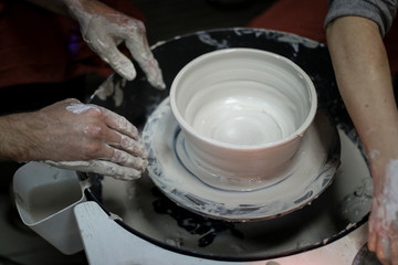 Hands of a Potter creating the clay.  Vessel on the Potter's wheel.
