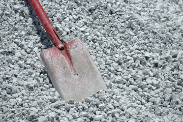 Fototapeta premium Shovel in piles of small rock in construction site