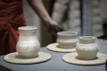 Unburned clay vases and pots on the table in the pottery. Raw clay pots ready for firing.