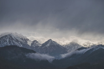 Fototapeta na wymiar Mountains covered in snow with dark cloudy sky in rainy day