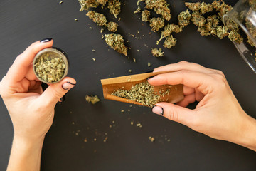 Woman preparing and rolling marijuana cannabis joint. Close up Woman rolling a marijuana joint. Pot...
