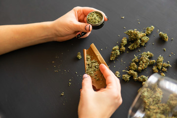 Woman preparing and rolling marijuana cannabis joint. Pot use concept. Close up Woman rolling a...