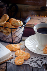Cookies with cheese in the form of eight on a wooden table with a cup of coffee on the background of books, selective focus