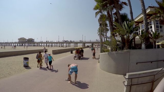 Timelapse view of people walking relaxed on beach sidewalk near Los Angeles enjoying the sun