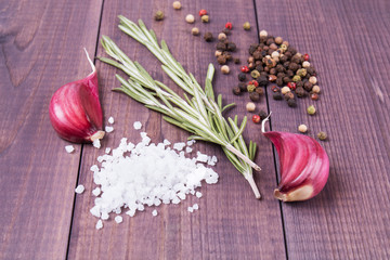 Cloves of garlic, rosemary, sea salt and pepper on wooden background