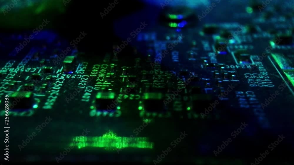 Poster pcb components on a motherboard with green ambient light. slow crawling shot on a slider.