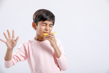 Cute indian/Asian little boy eating Mango with multiple expressions. isolated over white background