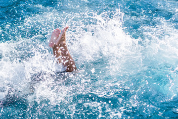 Legs of man jumped into water with splashes. Living a joyful fun life