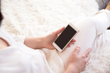 The girl in white holds the phone in his hands. Read the news on the phone. A man with a phone in his hands.