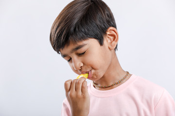 Cute indian/Asian little boy eating Mango with multiple expressions. isolated over white background