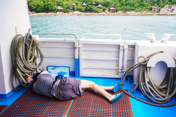 Man having sea sickness, sleeping at the back of the ship
