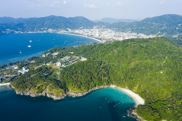 Obraz premium View from above, stunning aerial view of Patong city skyline in the distance and the beautiful Freedom Beach bathed by a turquoise and clear sea in the foreground, Phuket, Thailand.
