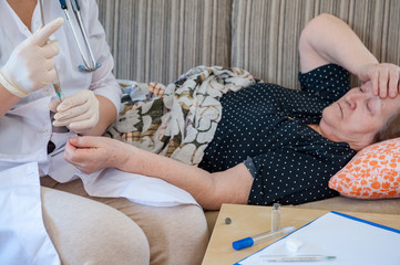 Pretty nurse in white coat helps sick retiree on social assistance program. Nurse carefully examines prescription of drugs, makes injections, measures blood pressure and cares.