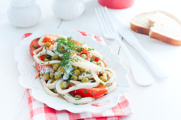 Salad of squid with tomatoes on a white dish, horizontal
