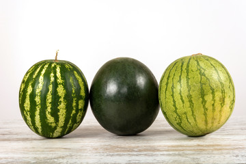 Three watermelons of different varieties, green and striped on a white background. Isolated, view straight, place for text.