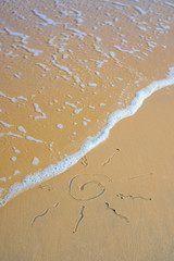 Sea calm wave washing away sun drawing on sand beach