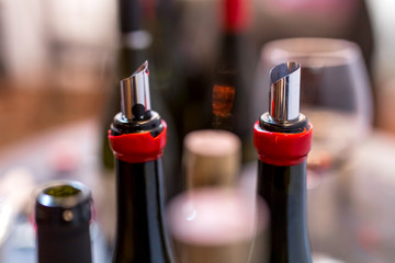 open wine bottles, flexible wine pourer, glasses, corks with blurred background at the wine tasting event
