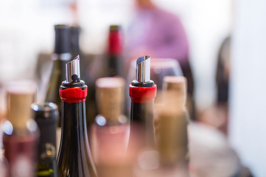 open wine bottles, flexible wine pourer, glasses, corks with blurred background at the wine tasting event
