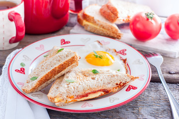 Breakfast with scrambled eggs and closed hot sandwich with cheese, tomatoes and sausage, horizontal