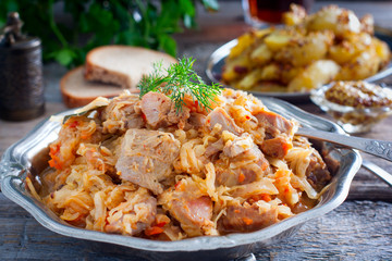 Braised cabbage with turkey thigh meat on a wooden table, horizontal