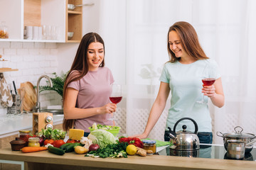 Healthy nutrition. Vegetarian diet. Cooking. Two young women with red wine glasses looking at foods assortment.