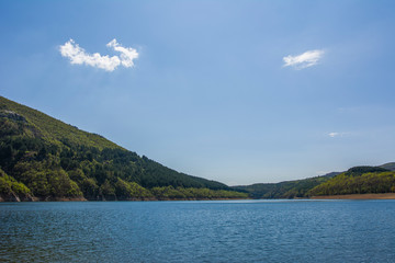 Mountain lake at summer. Blue sky with small white clouds 