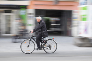 Aged man riding bicycle, motion blurred photography