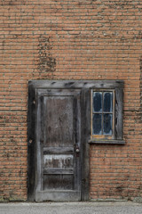 Old wooden door and small window in brick rustic grungy wall