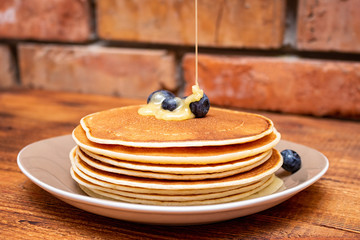 Pancakes with blueberries and honey on the dark brown wooden background