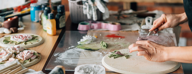 Artist at work. Studio workplace. Ceramic artwork in process. Handicraft. Woman with modeling tools in hand.