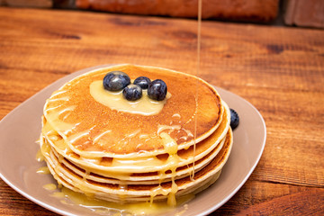 Pancakes with blueberries and honey on the dark brown wooden background
