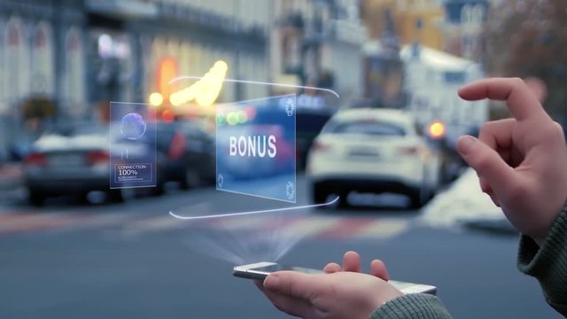 Female hands on the street interact with a HUD hologram with text Bonus. Woman uses the holographic technology of the future in the smartphone screen on the background of the evening city